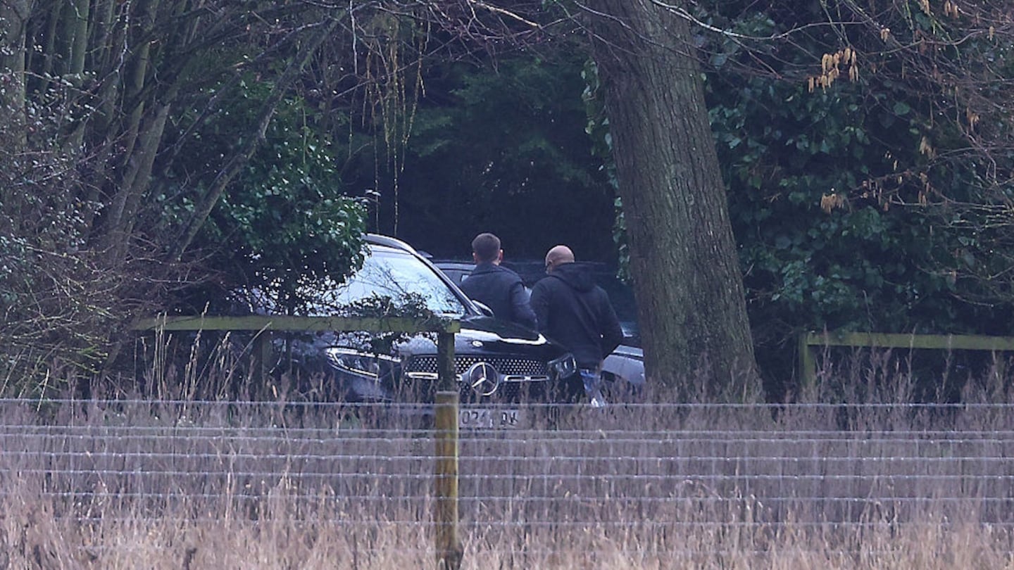 Men step out of an unmarked police car at the home of the former Prince Andrew on Thursday.